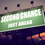 a green billboard with white words "second chance just ahead" with a sunset background