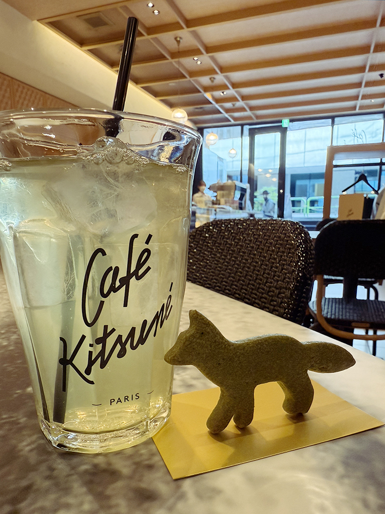 Iced green tea In a glass with Cafe Kitsune written on it. A fox-shaped sable next to the glass.