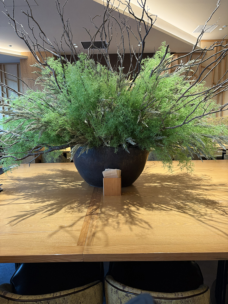 An ikebana display on the center counter of Kagurazaka Saryo features greens and branches.