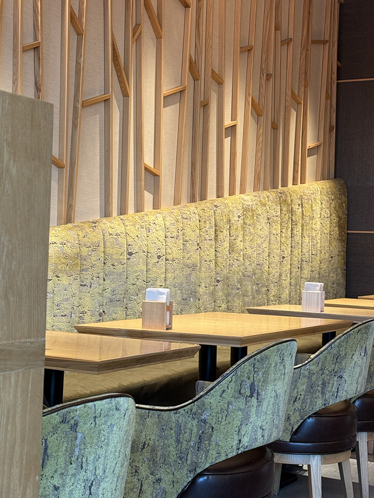 Interior of Kagurazaka Saryo with tables, chairs with green tea inspired palette and decorative wood background on the walls.