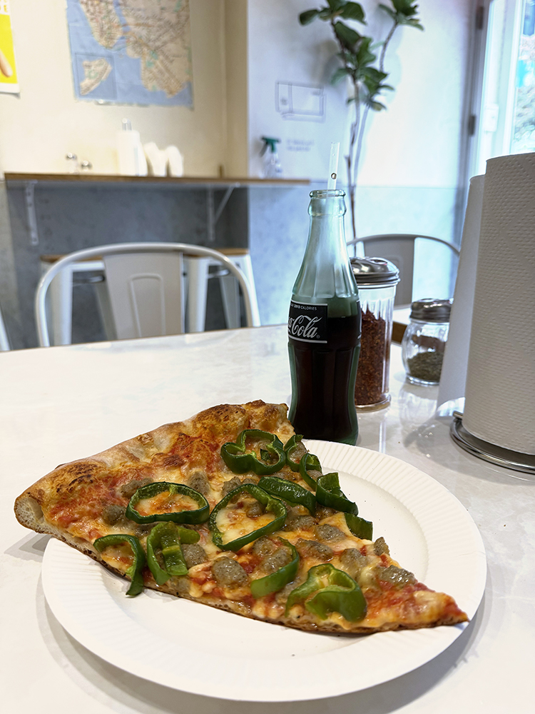 Photo of slice of pizza and a bottle of soda inside The Pizza Tokyo in Hiroo.